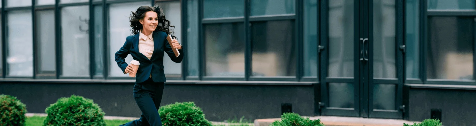 Foto de una chica con traje corriendo con un café en la mano